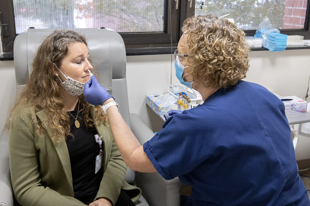 Cheryl Bath swabs Kelly Warren's nose to test for any reactions during her first visit to the COVID-19 vaccine trial run by MUSC and AstraZeneca.
