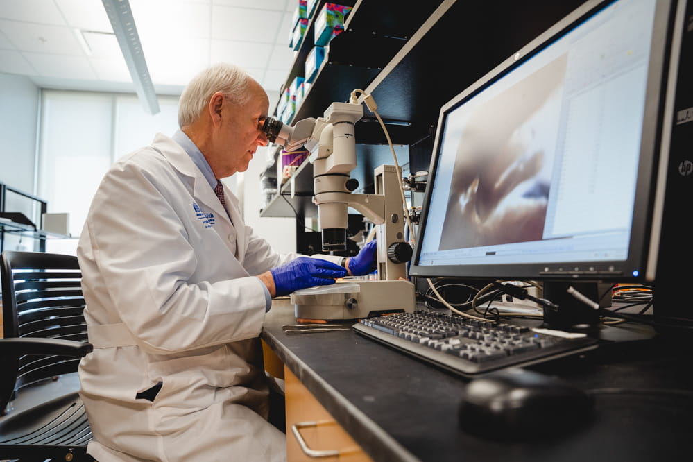 Dr. Raymond N. DuBois using microscope