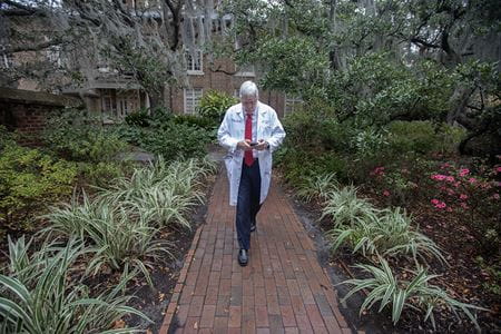 Cole walking through a garden while checking emails on phone