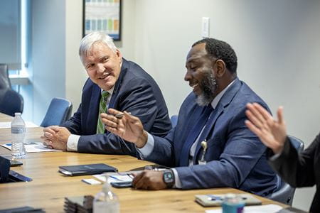 Cole and another man laugh about something before a meeting