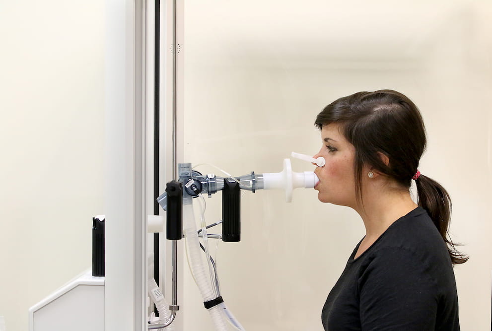 A photo of a woman breathing into a tube. 