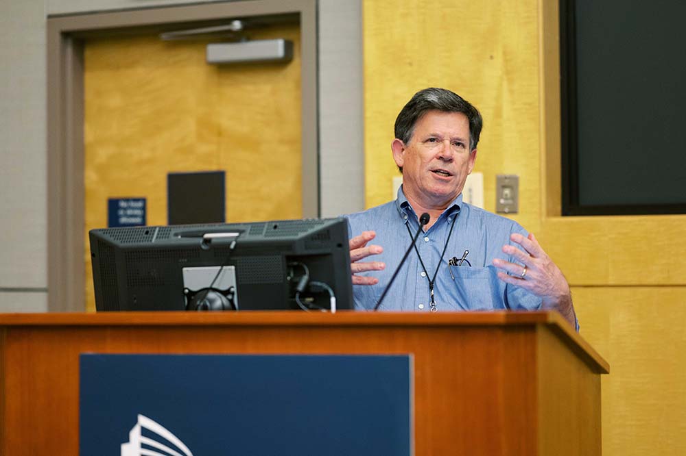 Man stands at a podium speaking to an audience.