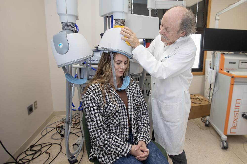Dr. Mark George demonstrates how the positioning arm of a transcranial magnetic stimulation machine can be placed on a person's head. 