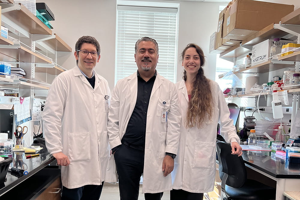 three researchers in white lab coats pose in the Sahin breast cancer research lab