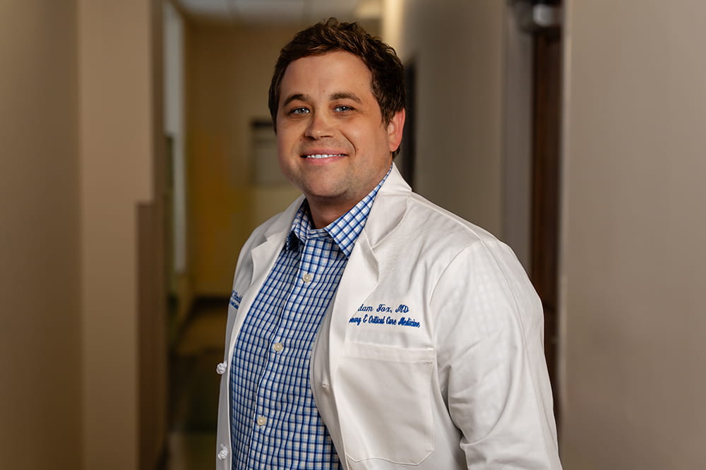 Adam Fox, M.D., pulmonologist and researcher, poses in a hallway at Hollings Cancer Center