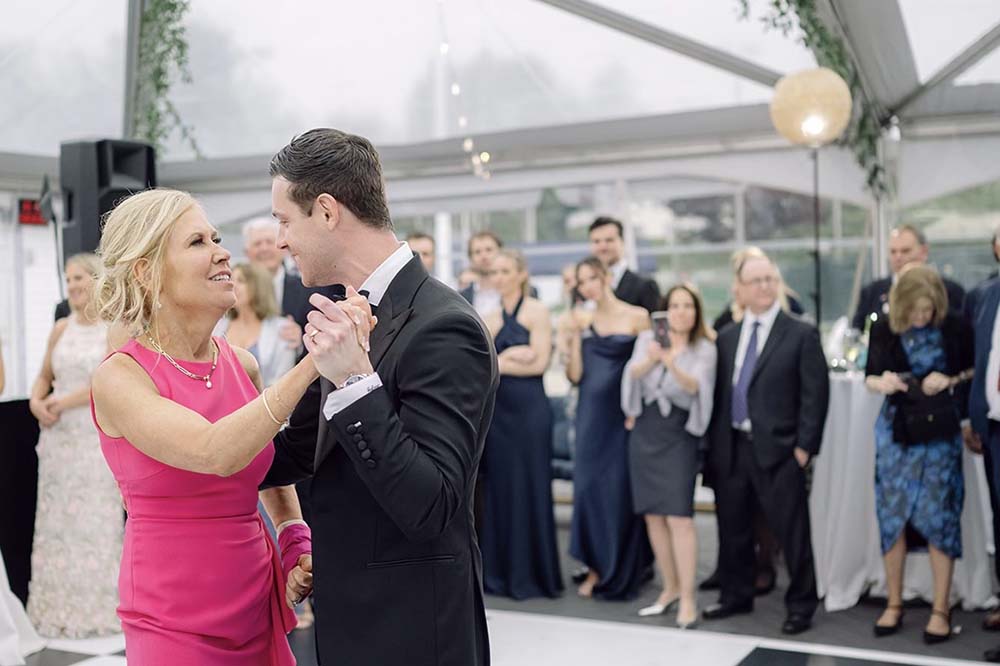 Woman in pink dress dances with young man in a tuxedo.