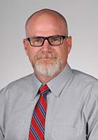 Man wearing eyeglasses and a shirt and tie.