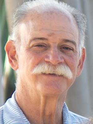 Headshot of a man with gray hair and mustache. He is wearing a blue collared shirt.