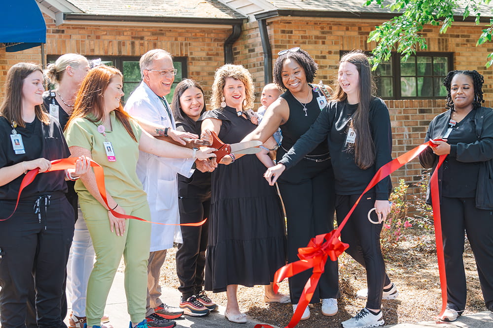 A doctor and his team celebrating at a ribbon cutting 