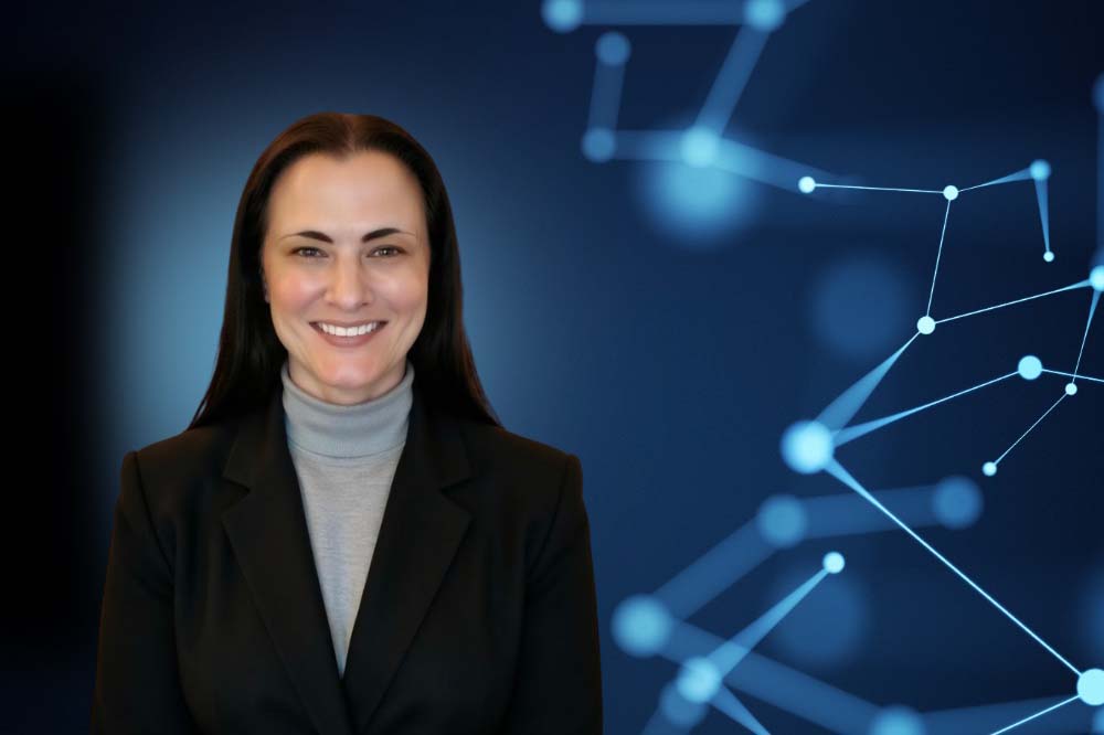 Women with long dark hair is on the left side of the picture. She is wearing a turtleneck and a dark blazer. On the right side are blue lines that connect via dots.