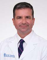 Man with dark hair wearing a white doctor's coat
