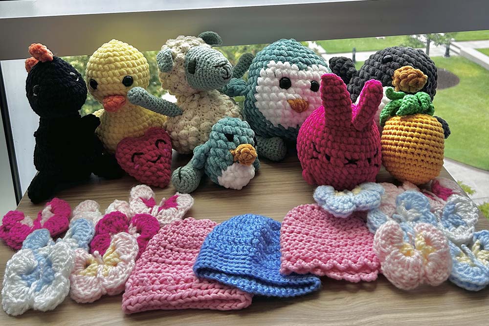 A row of soft toys and a row of little hats made by Healing Stitches Crochet Club.