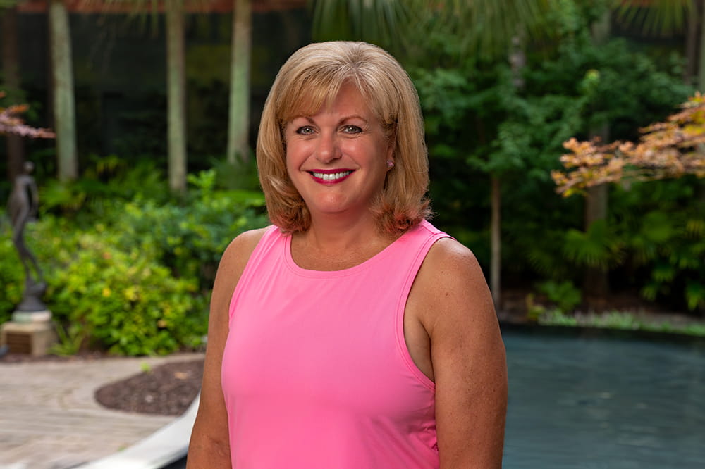 a woman in a pink tank top poses in a garden setting